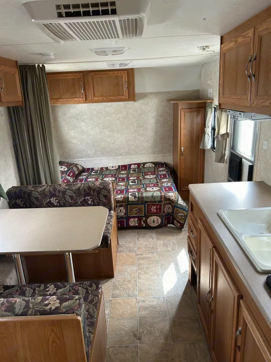 Inside an RV rental: a compact living space with bed, dinette, and kitchen amenities for travel.. Jag Jag II 2007