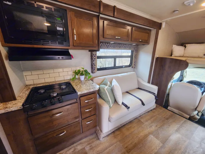 This RV rental offers a well-equipped kitchen (stove, microwave), a comfortable living area with a sofa, and an over-cab bunk.. Jayco Redhawk 2019