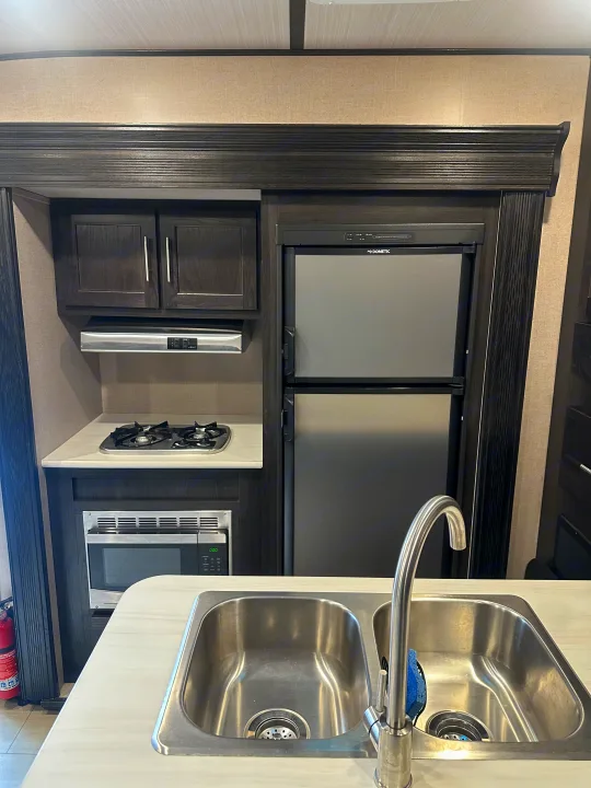 RV rental kitchen: This compact space features a dual-sink, two-burner stove, microwave, and a Dometic refrigerator.. Forest River X-Lite 2017