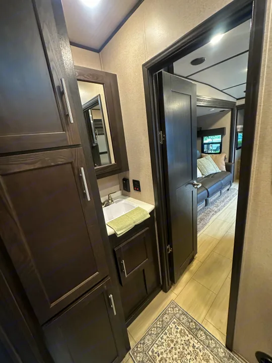 Explore this modern RV rental: bathroom with sink & dark cabinets, plus a spacious living area featuring a couch.. Forest River X-Lite 2017