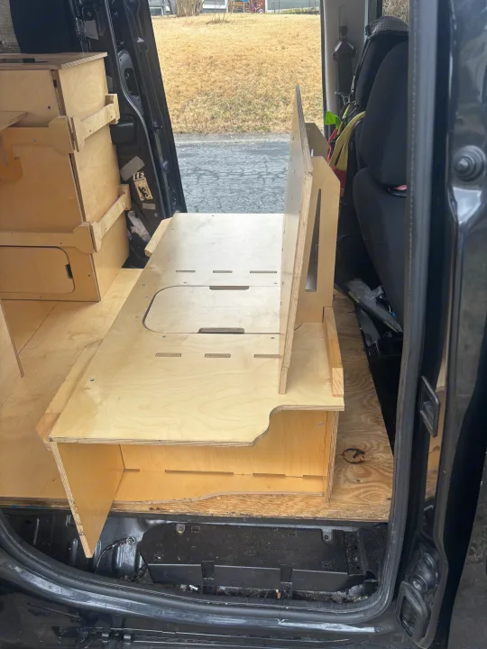 Custom modular wooden interior of an RV rental van, featuring clever storage units and sleeping platforms.. Ram Promaster City 2018