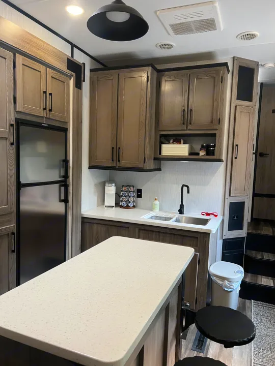 This RV rental offers a sleek kitchen area, featuring a Dometic fridge, ample counter space, and an island with bar seating.. Heartland RVs Fuel Toy Hauler 2022