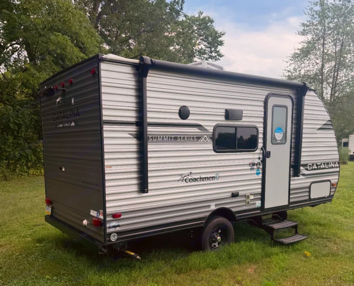 Compact gray travel trailer RV rental parked on grass, ready for your next adventure.. Forest River Coachmen Catalina Summit 2024