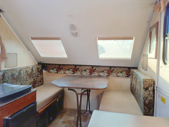 Bright RV rental interior featuring a dinette with floral bench seating, a wood table, and two large windows.. Forest River Flagstaff Classic 2014