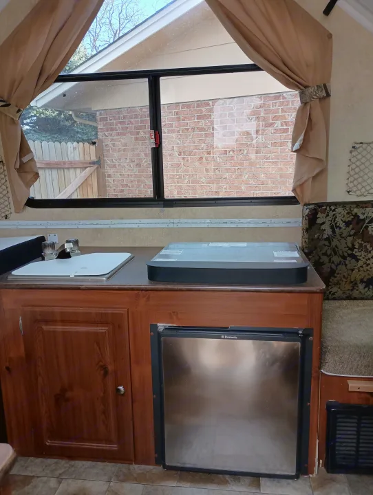 Compact RV rental interior featuring a kitchen area with a sink, stovetop, and a Dometic refrigerator.. Forest River Flagstaff Classic 2014