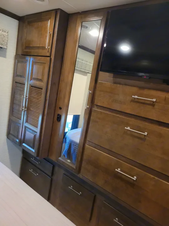 RV rental bedroom features: wood cabinetry, TV, mirror, and ample drawer/wardrobe storage.. Entegra Accolade 2020