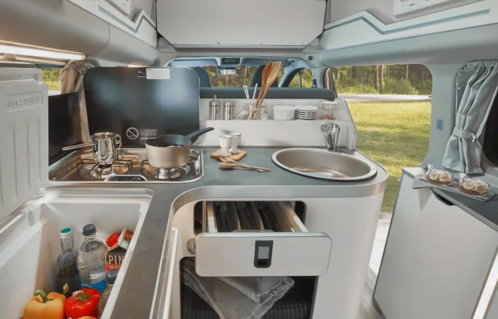 Compact camper van kitchen in an RV rental, showing a stove, sink, fridge, and storage for on-the-go cooking.. Ford Nugget 2025
