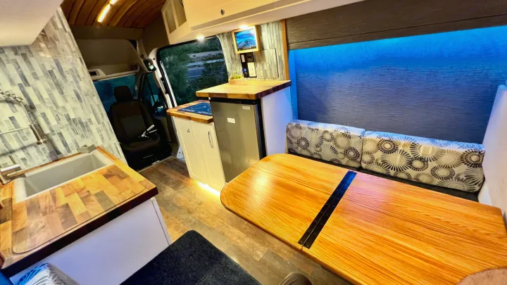 RV rental interior with kitchen, dining area, comfy seating, and blue ambient lighting for your next adventure.. Ford Transit 2019