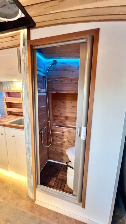 This RV rental boasts a compact interior with a wood-lined shower, blue light, composting toilet, and kitchen.. Ford Transit 2019