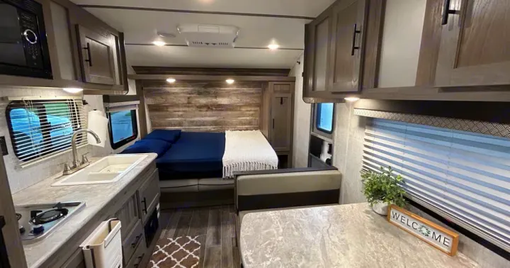 Modern RV rental interior: a cozy living space with compact kitchen, comfy bed, and dining area for adventures.. Gulf Stream Grand River 22Mb 2024