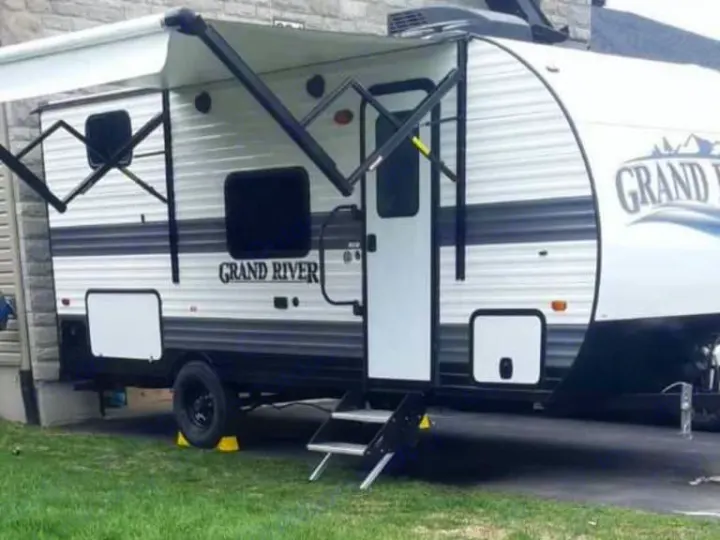 This "Grand River" travel trailer RV rental, with its extended awning and steps, is parked for an outdoor getaway.. Gulf Stream Grand River 22Mb 2024