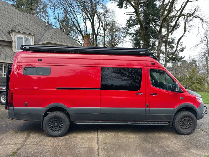 Custom bright red adventure van, ideal for rv rental. Features off-road tires, a roof rack, and a unique look.. Mercedes Sprinter 2022