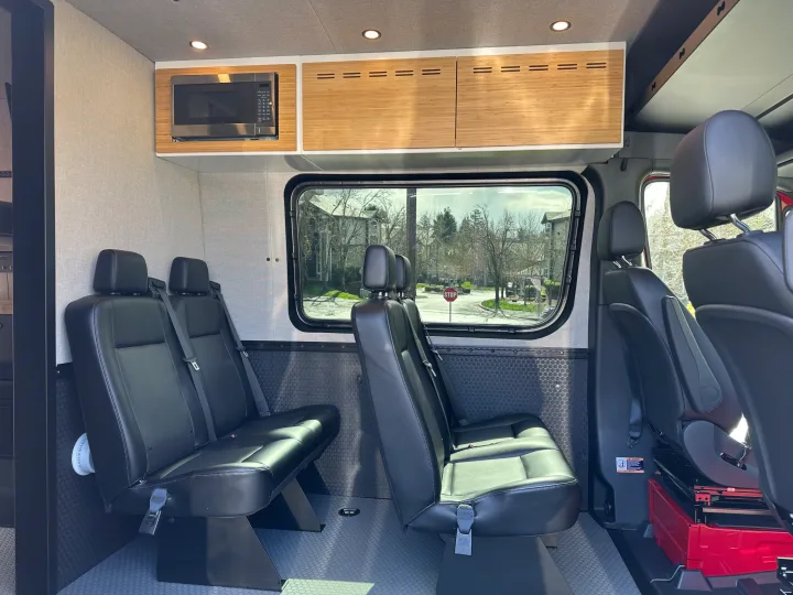 Spacious RV rental interior featuring passenger seating, microwave, and bamboo cabinetry for comfortable travel.. Mercedes Sprinter 2022