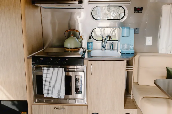 RV rental kitchen: modern, compact with stainless steel walls, wood cabinets, stovetop, oven, sink & coffee maker.. Airstream Flying Cloud 2017