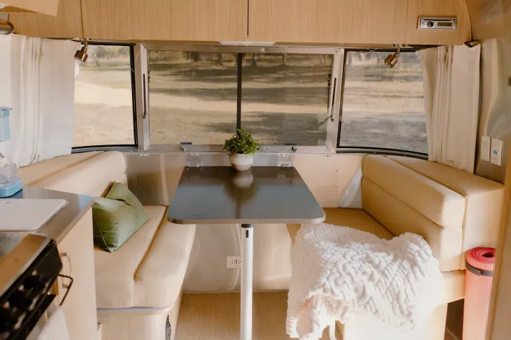 Cozy RV rental interior with a bright dining area, comfortable seating, and compact kitchen. Enjoy travel comforts!. Airstream Flying Cloud 2017
