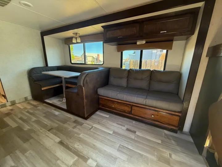 Inside an RV rental: a modern interior featuring a U-shaped dinette, comfy sofa with storage, and overhead cabinets.. Winnebago Minnie Winnie 2015