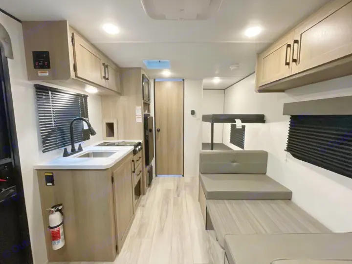Step inside this rv rental's interior: a compact kitchen, dinette, and bunk beds for family travel adventures.. Keystone Coleman Light 17BX 2025