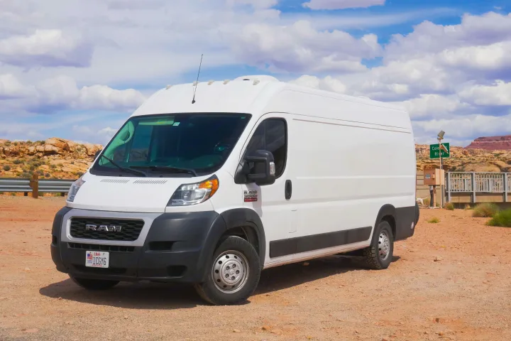 White Ram ProMaster RV rental van in Utah desert. This camper van is ready for adventures amidst rocky terrain under blue skies.. Ram Dodge Promaster 3500 2019