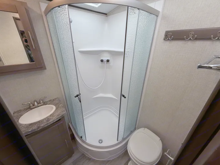 RV rental bathroom: compact and functional with a corner shower, sink vanity, toilet, and mirror cabinet.. Crossroads Sunset Trail Super Lite 2021