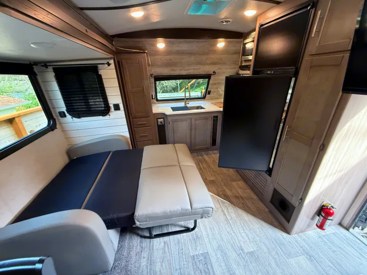 Bright RV rental interior showing a kitchen area, convertible sofa bed, & stylish wood-look floor.. Crossroads Sunset Trail Super Lite 2021