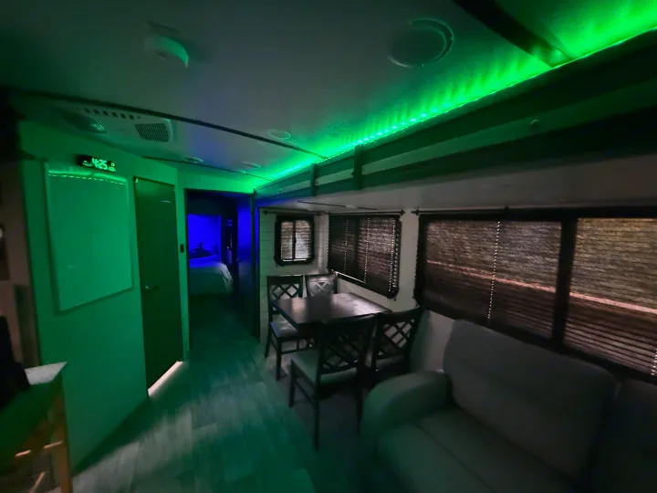This RV rental's modern interior features vibrant green LED lighting, a dining area, and comfy sofa for your travels.. Crossroads Sunset Trail Super Lite 2021
