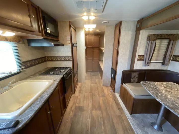 Inside this RV rental, a clean, functional kitchen, comfortable dinette seating, and bunk beds are visible, ready for travel.. Keystone RV Bullet Ultra Lite 2014