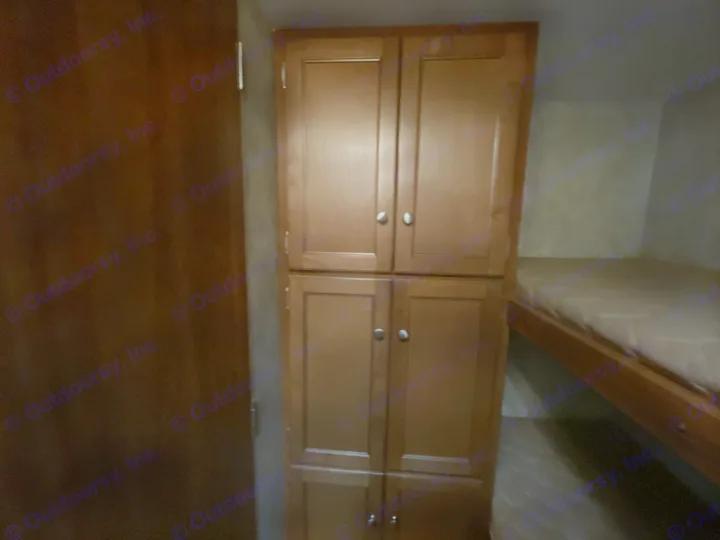 Inside an RV rental featuring wooden storage cabinets and comfortable bunk beds, perfect for family adventures.. Keystone RV Bullet Ultra Lite 2014