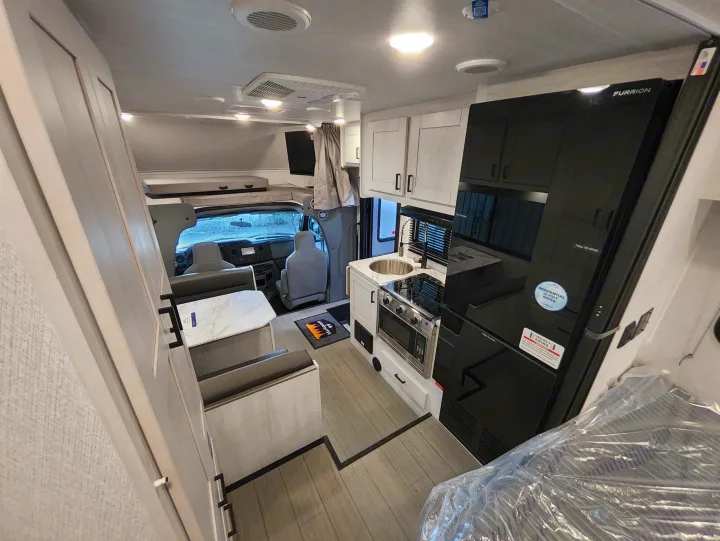 Bright RV rental interior: full kitchen, dinette area, and cab-over bunk. Designed for comfortable, compact travel.. East To West Entrada 2000NS 2025
