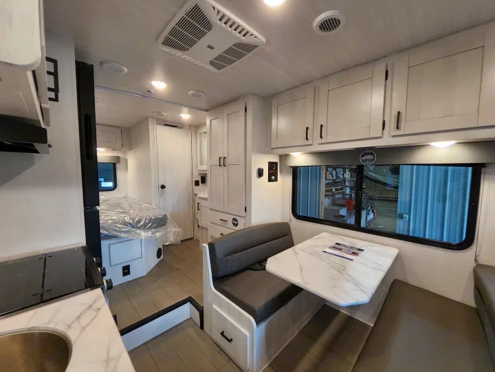 Step inside a modern RV rental with a bright dinette, kitchenette, and bed, showing a versatile compact living space.. East To West Entrada 2000NS 2025