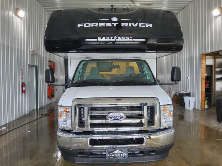 Front view of a white Forest River East to West RV rental inside a service bay with wet floors.. East To West Entrada 2000NS 2025