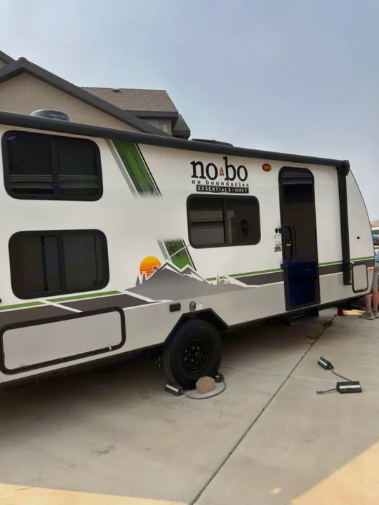 A white and gray No Boundaries travel trailer, ready for your next rv rental trip. See its mountain graphics & setup gear.. No Boundaries 19 Essentials Only 2024