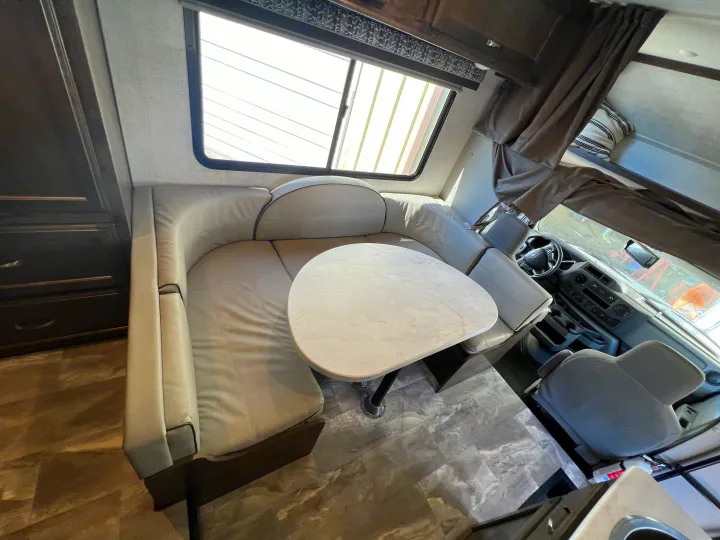 Spacious RV rental interior featuring a U-shaped dinette with table and a view of the driver's cockpit.. Gulf Stream Conquest 2023