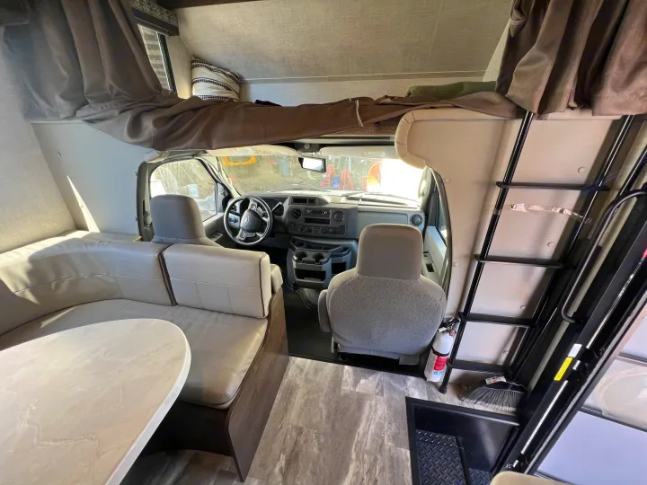 Spacious RV rental interior featuring a cozy living area with dinette, overhead bunk bed, and front cockpit, perfect for travel.. Gulf Stream Conquest 2023