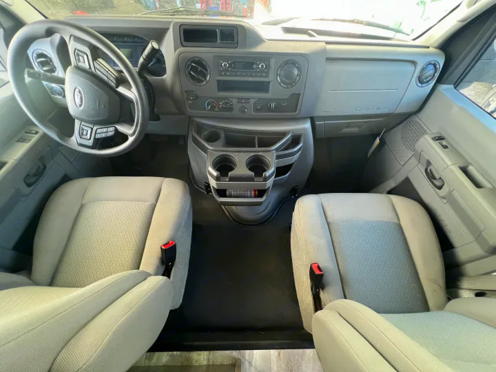 Clean RV rental interior featuring the steering wheel, organized dashboard, and comfortable front seats of a Ford E-Series van.. Gulf Stream Conquest 2023