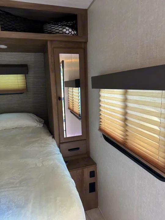 This RV rental's bedroom features a comfortable bed, mirrored closet, window blinds, and handy USB outlets.. Keystone RV Springdale 2020