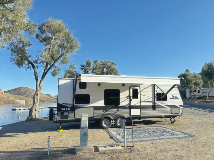 **RV rental** by the lake: A travel trailer set up at a sunny campsite with mountain views.. Jayco Jay Flight SLX 2022