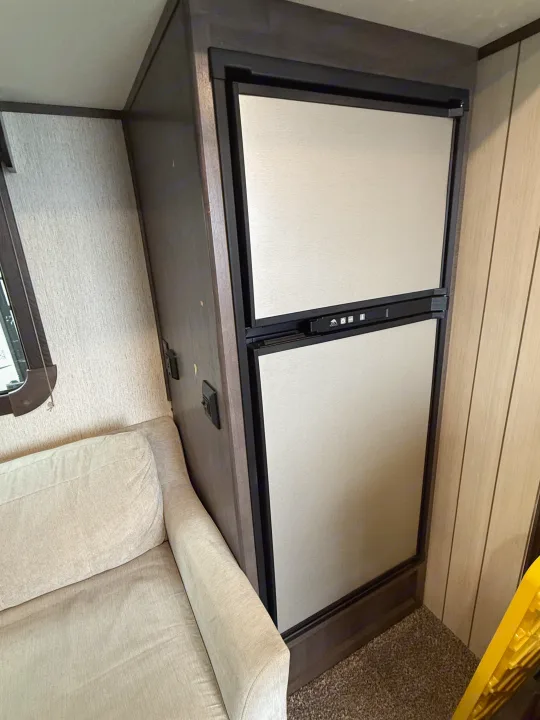 Inside an RV rental: a modern two-door refrigerator and a comfortable sofa, designed for compact living on the go.. Crossroads Sunset Trail Super Lite 2019
