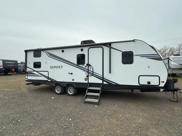 White Sunset Trail travel trailer for rv rental, parked on gravel. Perfect for camping adventures.. Crossroads Sunset Trail Super Lite 2019