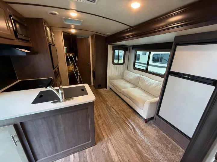 Explore this RV rental's inviting interior: functional kitchen, cozy living space with a sofa, and versatile sleeping options.. Crossroads Sunset Trail Super Lite 2019