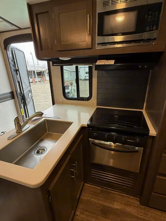 RV rental kitchen: modern design with sink, Suburban stove/oven, High Pointe microwave, and ample counter space.. Crossroads Sunset Trail Super Lite 2019