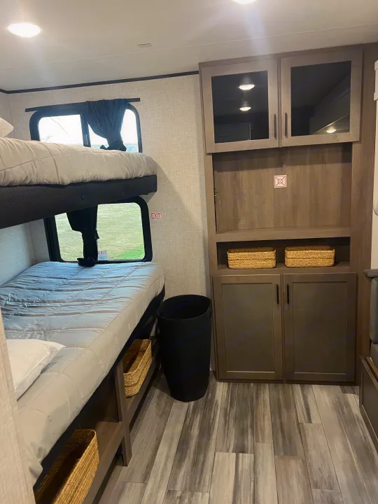 RV rental bunk room with dual beds, clever storage solutions like baskets and cabinets, and wood-look flooring.. Jayco Jayflight 324bds 2025
