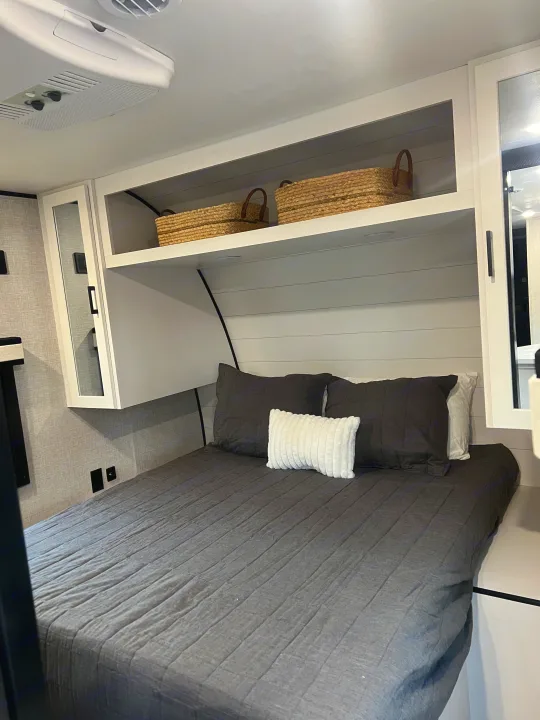 Step inside this RV rental's bedroom, showcasing dark grey bedding, overhead storage, and white shiplap walls.. Jayco Jayflight 324bds 2025
