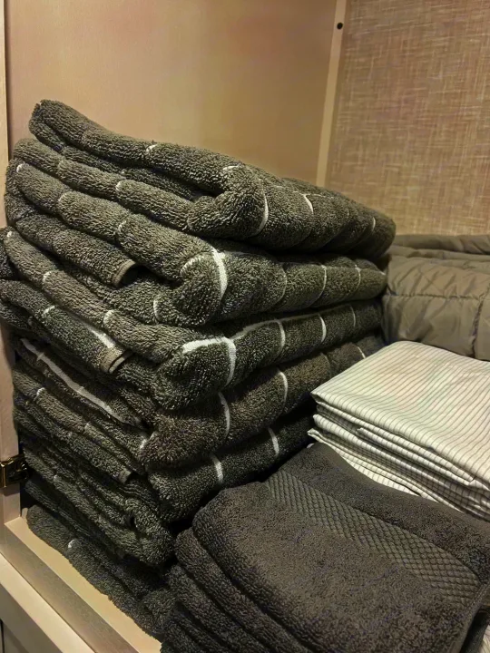 Neatly stacked grey towels & striped linens organized in a cabinet for your comfortable RV rental trip.. Jayco Jayflight 324bds 2025
