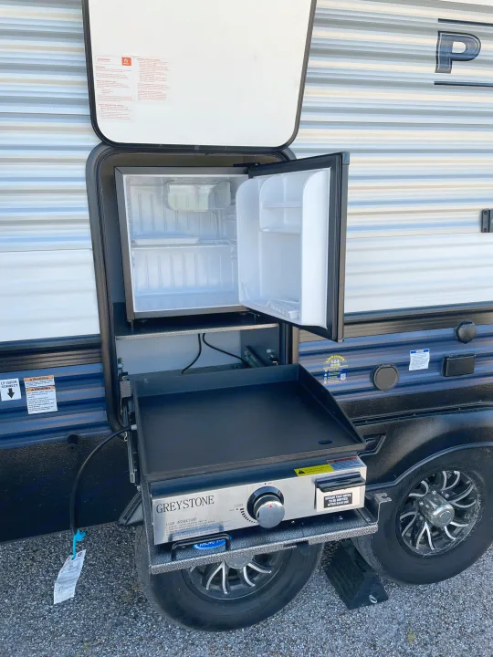 This RV rental's outdoor kitchen boasts a Greystone griddle and mini-fridge for convenient cooking on trips.. Palomino Puma 337BH 2025