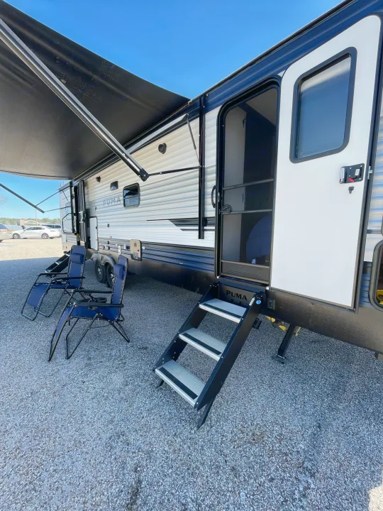 Puma RV rental with extended awning, steps, and outdoor chairs on gravel. Your next adventure awaits!. Palomino Puma 337BH 2025