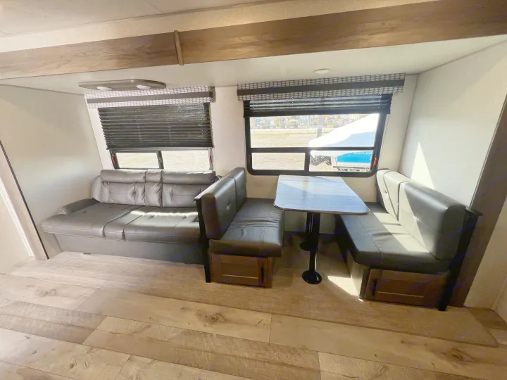 Spacious RV rental interior featuring a comfy L-shaped couch, dinette with table, and large windows. Ideal for travel.. KZ Confluence 2022