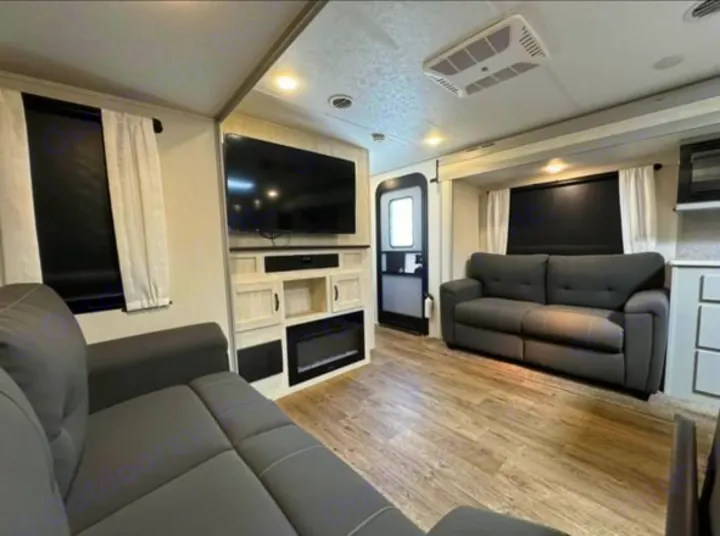 Explore this RV rental's cozy living space! Features two comfy sofas, TV, and an electric fireplace.. Forest River Vibe 2022