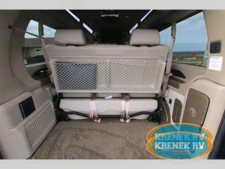 Spacious RV rental interior featuring flexible tan rear seating and cargo area with mesh storage for comfortable travel.. Chevrolet Explorer Luxury Van 9 Passenger 2023