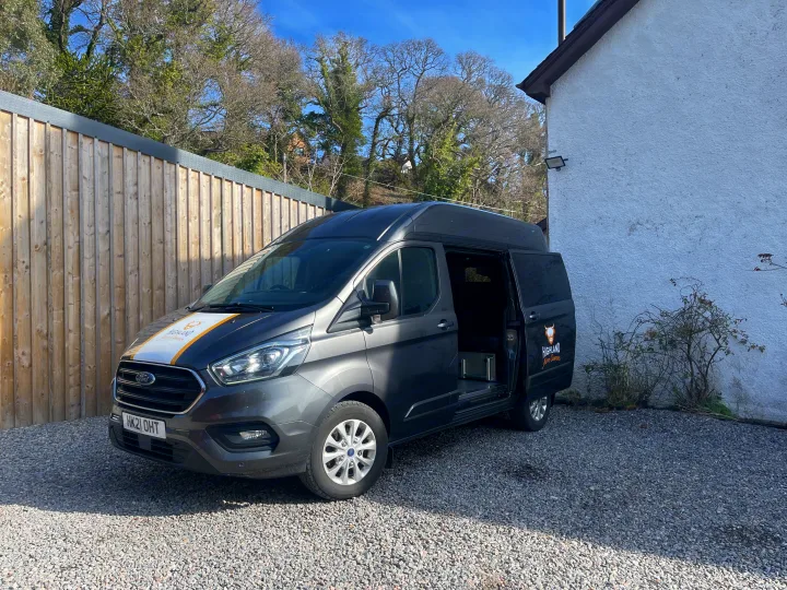 A dark grey Highland Auto Campers Ford campervan for RV rental, with its side door open, parked on a gravel driveway.. Ford Transit Custom 2 berth Hi-line Automatic 2021
