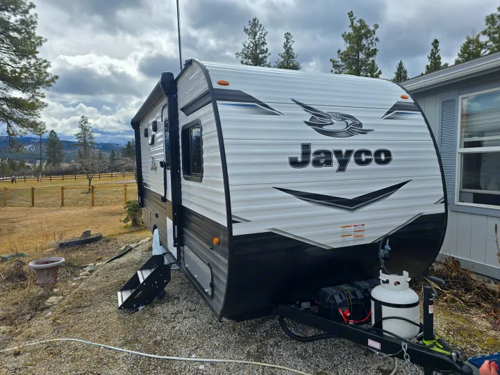 A Jayco travel trailer RV rental, equipped and parked outdoors in a scenic, cloudy landscape.. Jayco Jay Flight SLX 2024